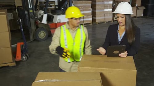 Workers using digital tablet in shipping warehouse