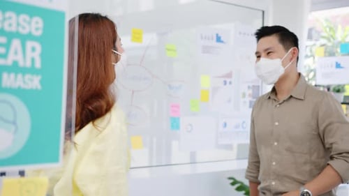 Two Colleagues Elbow Bump Safely Wearing Face Masks