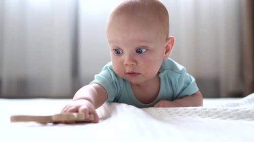 Cute Infant Playing with Toy on White Blanket