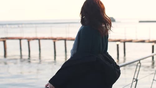 Young Beautiful Woman Walks and Enjoys the Sea on a Warm Winter Day