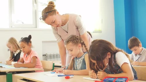 Teacher Helping Kids with Their Homework in Classroom at School