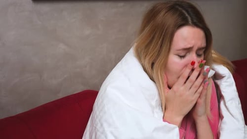 Woman Wrapped in Blanket Sitting on Couch Crying