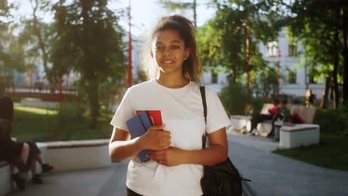 Mixed Race Female Student Holding Books in University Campus Smiling Looking at Camera
