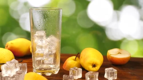 Pear Juice Poured Into Glass on Green Garden Background