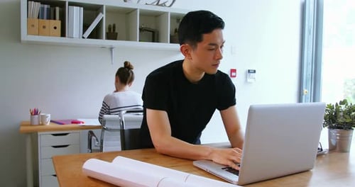 Young Adult Working on Laptop in Bright Workspace