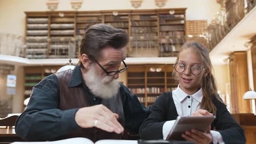 Girl and Senior Man Studying in Library