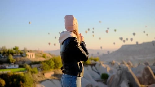 Bonita mujer esbelta con sombrero rosa y chaqueta de cuero negra se calienta las manos con el aire de su boca en