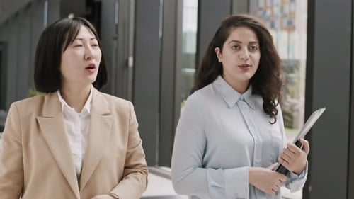Two Businesswomen Going along Office Hall and Talking