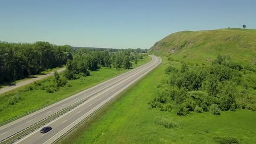 Luftbild: Tiefflug über den Highway in den Highlands. Blick auf den Wald, vorbeifahrende Autos, Lastwagen