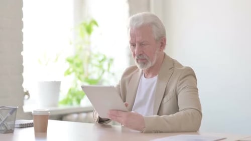 Old Man Using Tablet While Sitting in Office