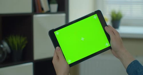 Young Man Holding TabletPC in Hands, Playing Mobile Game. TabletPC with Green Screen in Chroma Key.