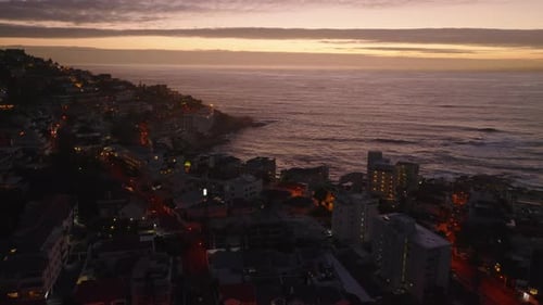 Fly Above Buildings in Urban Neighbourhood at Sea Coast at Dusk
