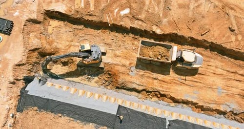 Excavator Loads Dump Truck at Construction Site