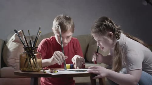 Two Children Painting Together at a Table Indoors