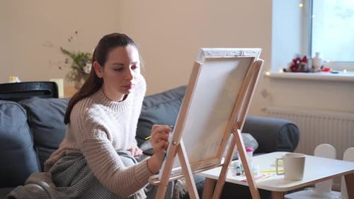 Woman Paints on Canvas in Cozy Home Interior