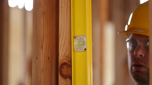 Construction Worker Using Level on Wooden Beams