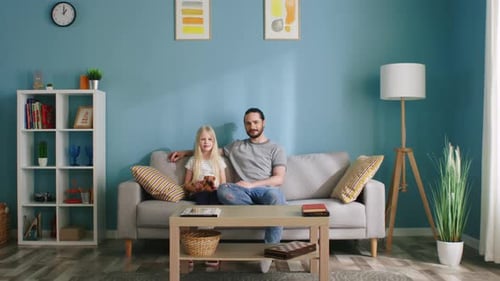 Man and Child Sitting Together on Sofa Indoors