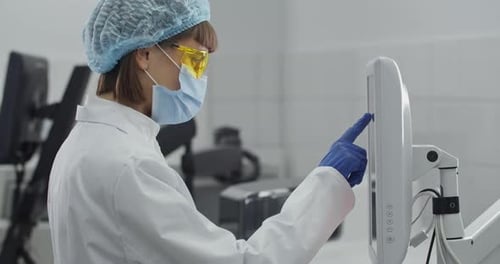 Woman in Lab Coat Uses Touchscreen Monitor