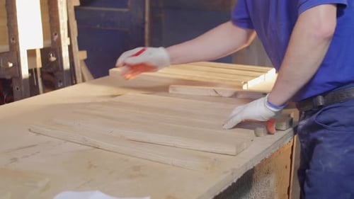Man Measures Wood Planks in Workshop
