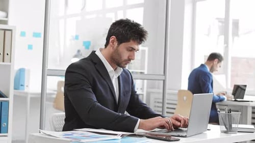 Trabajador masculino escribiendo en una computadora portátil