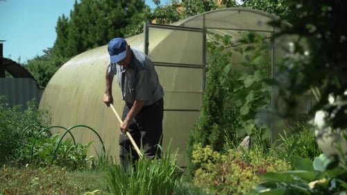 Un homme âgé travaille dans le jardin avec des outils de jardinage.