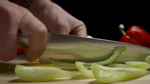 Hands of Man with Knife Dicing Yellow Sweet Pepper