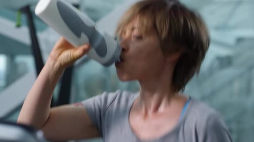 Woman Exercising on Treadmill and Drinking Water