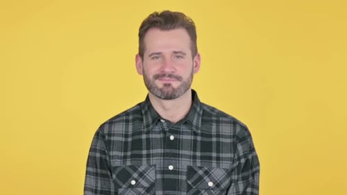 Man Smiles Slightly at Camera on Yellow Background