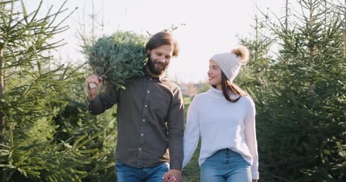 Man Carrying on Shoulders Fir Tree and Holding Hand his Wife During Leaving Special Place