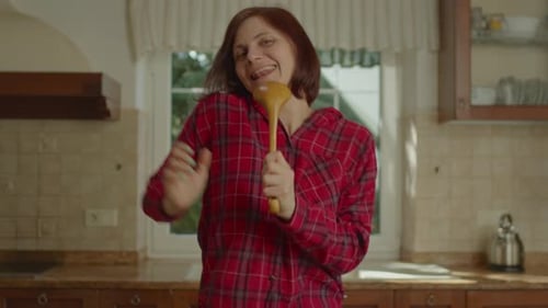 Woman Singing and Dancing with Spoon in Kitchen
