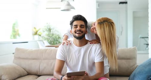 Loving Couple Embracing at Home, Man Uses Tablet