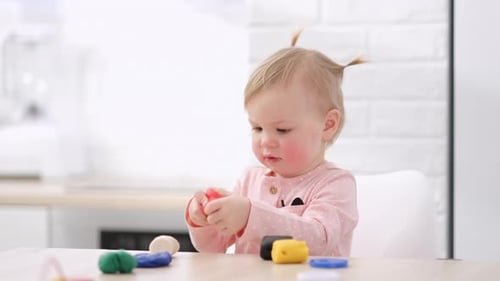 Adorable Baby Playing with Colorful Dough at Table