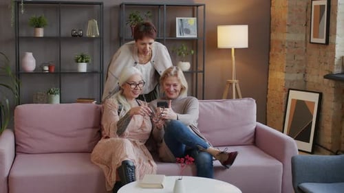 Mature Women Enjoying Smartphone Together on Couch