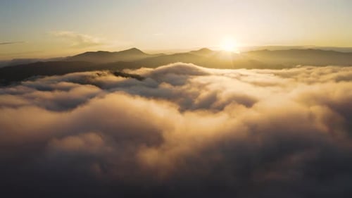 Voe pelas nuvens acima das montanhas ao pôr do sol. Voando sobre neblina ao nascer do sol