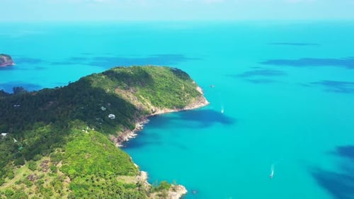boats sailing in the turquoise gulf of Thailand. Tropical island with palm forest and elevated coast