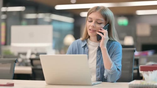 Woman Talking on Phone at her Computer