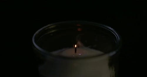 Slow motion close up footage of a white candle on a dark background