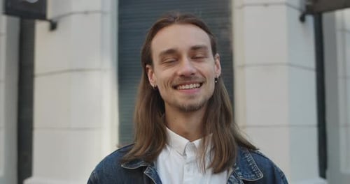 Close Up View of Cheerful Long Haired Man Turning Head and Looking To Camera. Handsome Young Guy