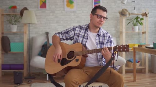Man Plays Acoustic Guitar at Home