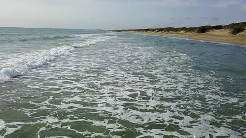 Sandy Beach with Choppy Rough Sea Under Dense Clouds Covering Sky. Aerial Survey. Slow Motion