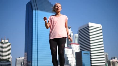 Young Fitness Woman In Active Wear And Wireless Earphones Dancing In City