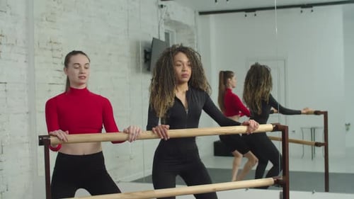 Women Stretching at Ballet Barre in Bright Studio