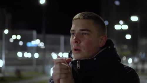 Young Man Rubbing Hands Together Outside at Night