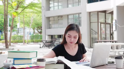 Asian student read books and do academic business research with computer laptop study lessons.