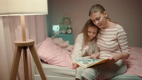 Mother Reading Story to Daughter in Bed at Night
