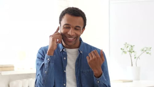 Man Answers Phone and Smiles During Cheerful Conversation