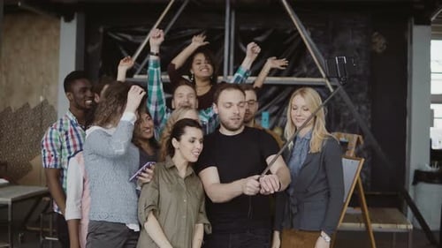 Happy Team Takes Selfie at Loft Office. Man Holds Smartphone with Self-stick and Takes Photo of