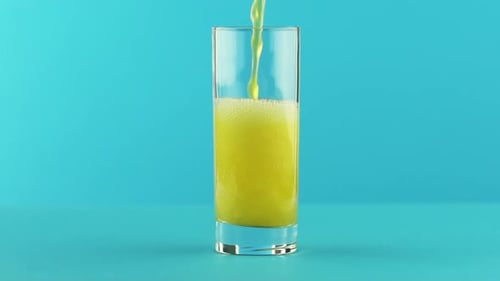 Yellow Drink Poured into Glass on Light Blue