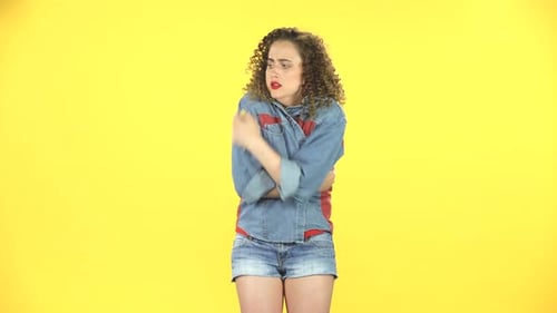 Belle fille gelée et essayant de se réchauffer sur fond jaune au studio