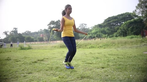 Woman Jumping Rope in a Grassy Field